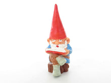 UpperDutch:,1 (ONE) Gnome, miniature Gnome after a design by Rien Poortvliet, Brb. David the Gnome, reading gnome sitting on a tree trunk.