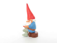 UpperDutch:,1 (ONE) Gnome, miniature Gnome after a design by Rien Poortvliet, Brb. David the Gnome, reading gnome sitting on a tree trunk.