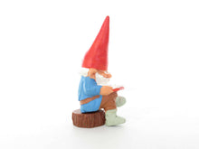 UpperDutch:,1 (ONE) Gnome, miniature Gnome after a design by Rien Poortvliet, Brb. David the Gnome, reading gnome sitting on a tree trunk.