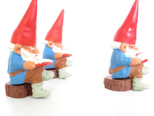 UpperDutch:,1 (ONE) Gnome, miniature Gnome after a design by Rien Poortvliet, Brb. David the Gnome, reading gnome sitting on a tree trunk.